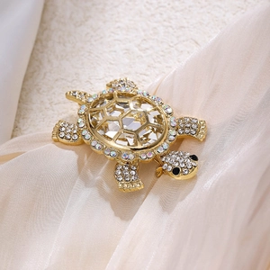 Close-up of golden turtle brooch with large faceted crystal and shimmering rhinestones