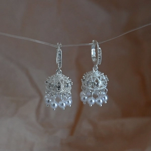 Detail of silver bell-shaped earrings with zircon inlay and hanging pearl tassels