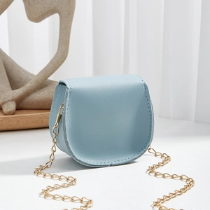 Minimalist blue mini square lipstick bag with gold chain strap on a white table