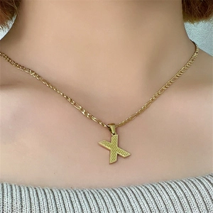 Dettaglio ravvicinato di una collana in acciaio inossidabile dorato con ciondolo lettera X