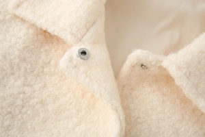 Detail of cream white faux shearling fabric texture with metallic snap button closure