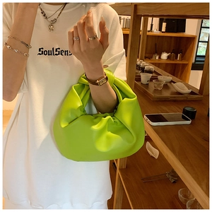 Detail of a lime green pleated cloud bag with a unique twisted handle in minimalist style