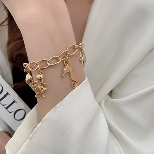 Detailed close-up of a gold-finish marine charm bracelet with seahorse and starfish motifs