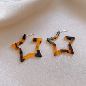 Close-up of star-shaped earrings with tortoiseshell leopard pattern on silk fabric