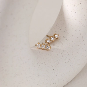 Elegant gold-plated stainless steel stud earrings with four zircon stones on a ceramic stand