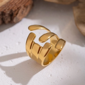 Irregular liquid gold ring with molten lava texture on white stone and wood background
