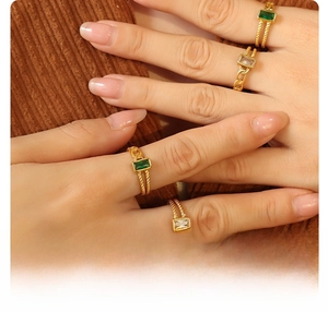 Detail of 18k gold plated titanium rings with emerald and clear zircon inlay