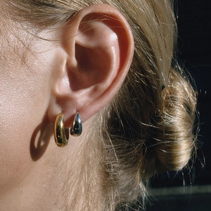 Détail de boucles d'oreilles goutte d'eau épaisses en finitions or et argent polies