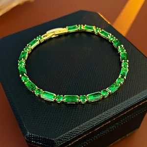 Primer plano de pulsera bañada en oro con circonitas esmeralda y cierre de seguridad