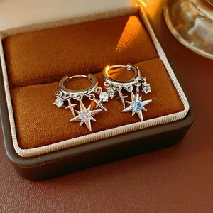 Macro shot of silver star pendants with sparkling zircons in a brown velvet jewelry box