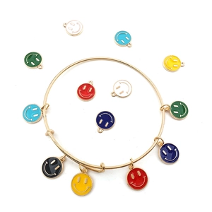 Flat lay of colorful enamel smiley face charms and a gold adjustable metal bracelet