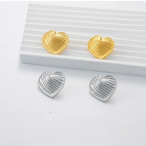 Detail of heart-shaped stainless steel earrings in gold and silver with ribbed texture