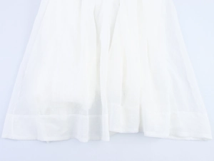 Détail de l'ourlet d'une robe en mousseline blanche avec tissu transparent raffiné