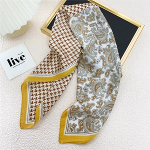 Elegant silk scarf with golden houndstooth and paisley patterns on a frame