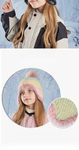 Detailed view of rainbow gradient knit hat with fuzzy earflaps and large pink pompom