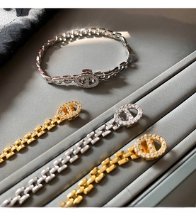 Macro detail of gold and silver chain bracelets with white zircon pavé in a velvet tray