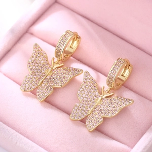 Macro detail of gold butterfly earrings with pink cubic zirconia in a velvet box