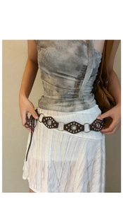 Detail of bohemian dark brown leather belt with diamond shapes and silver metal rings