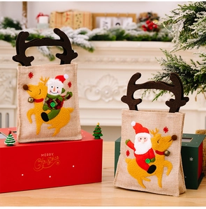 Detailed view of burlap Christmas bags with Santa and Snowman designs and reindeer antlers