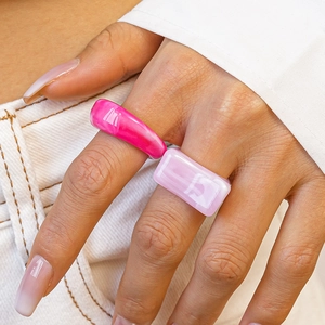 Pink and lilac acrylic resin geometric rings set worn by a model in a minimalist style