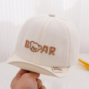 Detail of white baby sun hat showing brown bear embroidery and soft cotton fabric