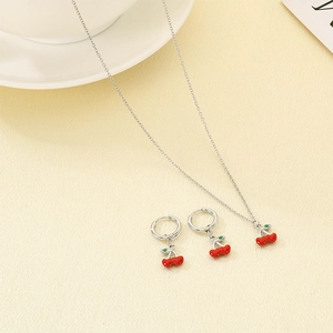 Detail view of silver cherry jewelry set including necklace and earrings on table