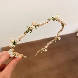 Macro detail of elegant lily of the valley headband with pearls and gold wire craft