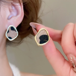 Macro shot of irregular leopard print earrings with gold plating and textured flocking