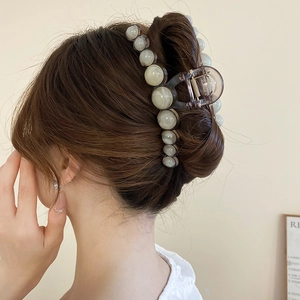 Detailed side view of a large translucent grey resin hair claw clip with cream faux pearls