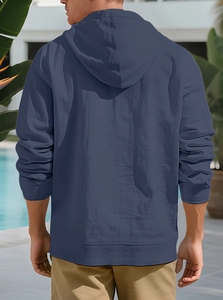 Outdoor back view of man in navy blue linen blend hoodie with tropical resort pool background
