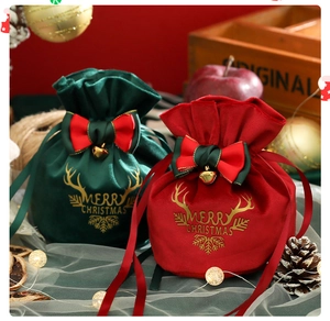 Close-up of velvet Christmas gift bags with gold bells and Merry Christmas embroidery