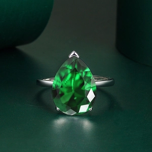 Detailed close-up of a pear-cut emerald gemstone ring with three-prong silver setting