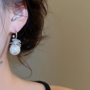 Nahaufnahme eines silbernen C-förmigen Perlenohrrings mit Zirkonia-Akzenten am Ohr