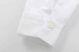 Close-up of white cotton shirt cuff featuring a single button and fine fabric texture