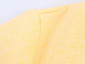 Dettaglio del tessuto in tweed giallo che mostra la trama e la qualità delle cuciture