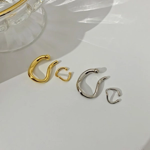 Detail of minimalist gold and silver geometric ear cuff set with metallic luster finish