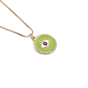 Macro detail of gold-plated evil eye pendant with green enamel and clear zircon stones
