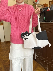 Cute cat-shaped canvas tote bag with 3D ears and bow tie shown in a lifestyle shop setting