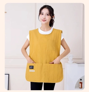 Detail of a yellow waterproof apron vest with large front pockets and a brand label