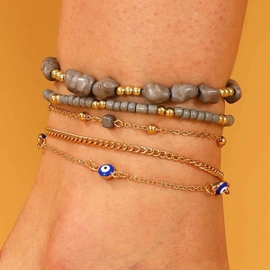 Detalle de set de cinco pulseras bohemias con cuentas de piedra gris y amuleto ojo turco