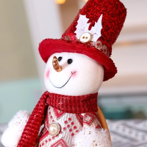 Detail einer Weihnachts-Schneemann-Puppe mit roten Pailletten und Stricktextur im Fokus