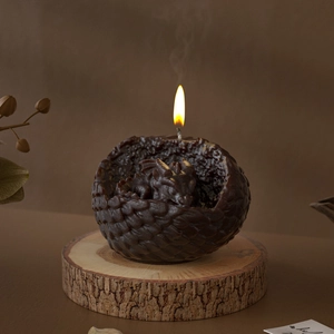 Macro shot of a burning dragon egg candle featuring a detailed baby dragon resin sculpture
