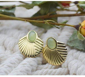 Detailed macro view of gold fan-shaped stud earrings with green natural stone insets