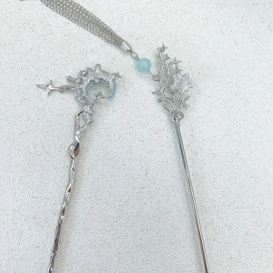 Detailed close-up of moon and coral-shaped silver hair sticks with blue beads and tassels