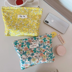 Dettaglio di pochette in cotone a fiori con etichetta Simple Wish e chiusura lampo