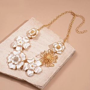 Close-up of golden floral necklace with white enamel petals and sparkling rhinestone centers
