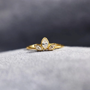 Macro shot of crown-shaped gold ring with marquise-cut gems on textured grey felt