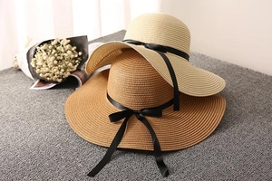 Close-up of woven straw sun hats with black ribbons in beige and caramel tones