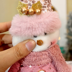 Detail of pink sequin hat and soft plush texture on decorative Christmas snowman doll