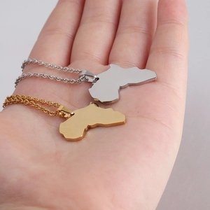 Close-up of gold and silver Africa map pendants with mirror finish on a palm
